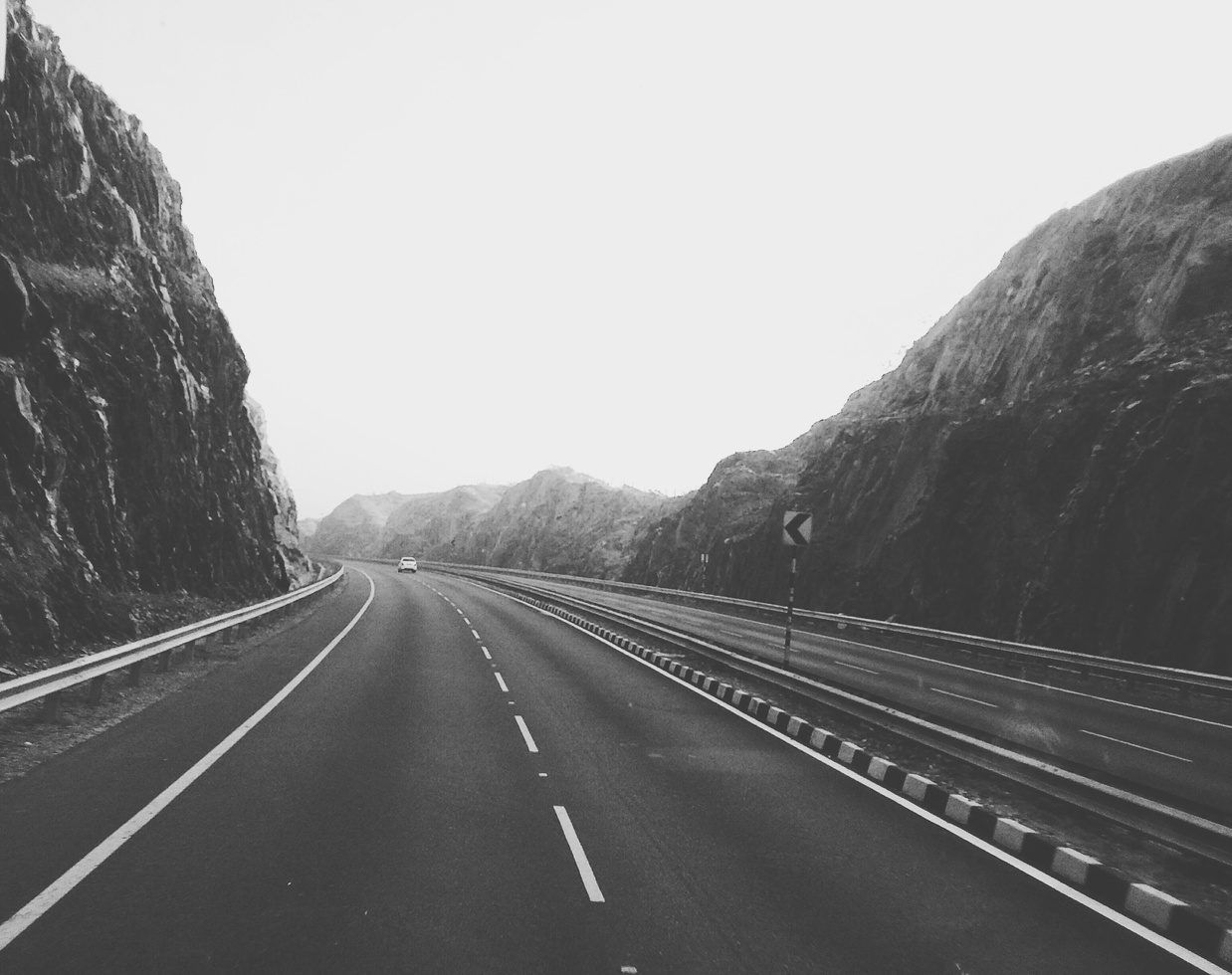 Schwarz-Weiß-Foto einer leeren Straße, die zwischen steilen Felswänden in die Berge führt