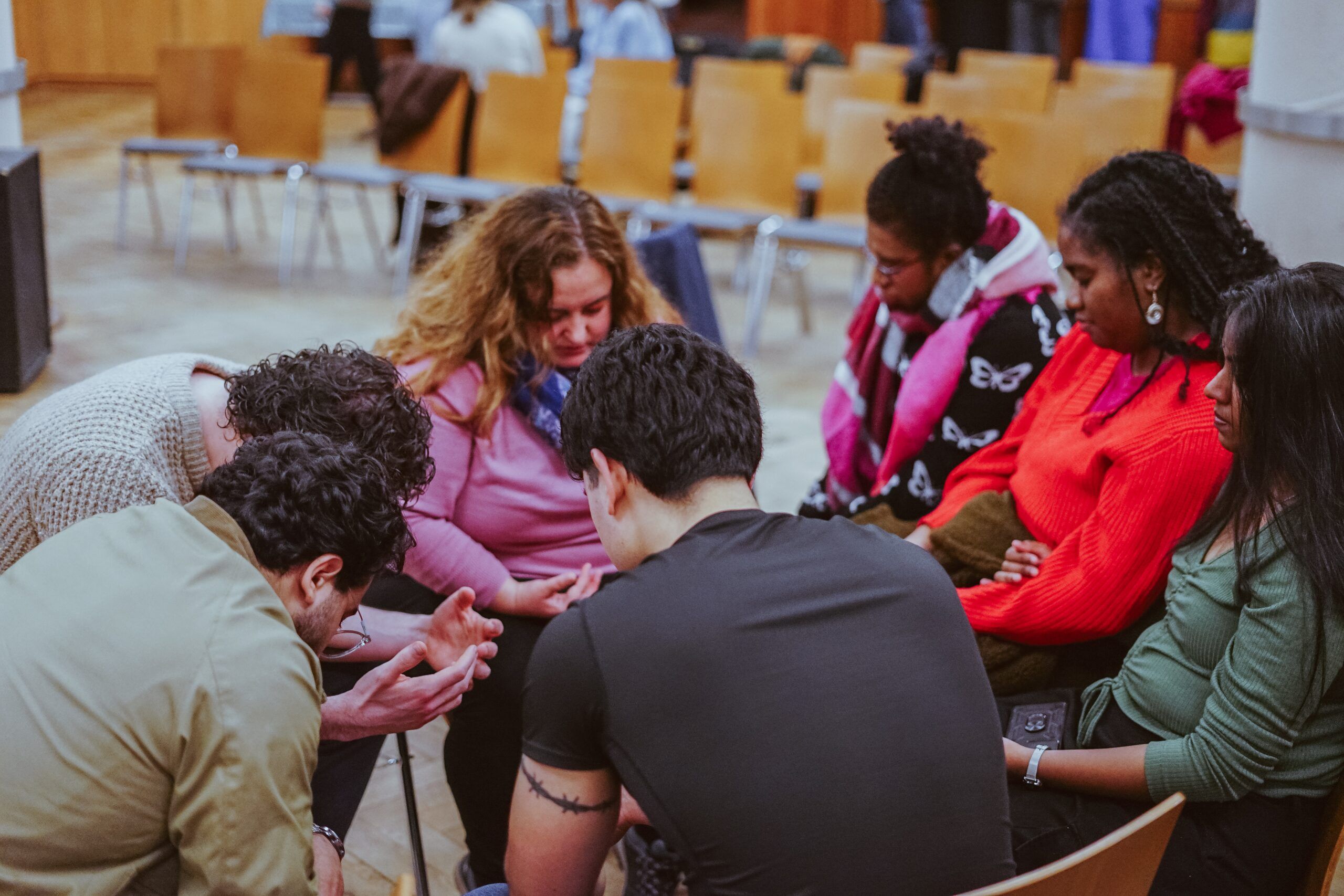 A small group sitting in a circle, praying together